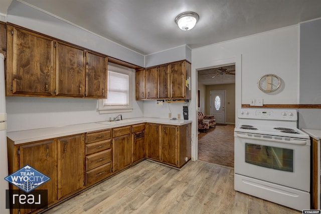 kitchen featuring electric stove, light countertops, light wood finished floors, a sink, and brown cabinets