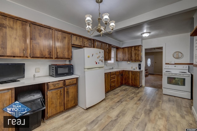kitchen featuring white appliances, light countertops, a chandelier, and light wood-style flooring