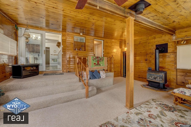 unfurnished living room with a wood stove, carpet flooring, wood walls, wooden ceiling, and beamed ceiling