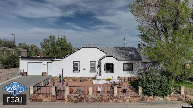 view of front of home with a fenced front yard, driveway, an attached garage, a gate, and stucco siding