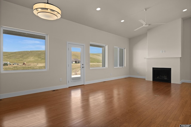 unfurnished living room featuring a fireplace, hardwood / wood-style flooring, a ceiling fan, recessed lighting, and baseboards