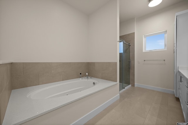 full bathroom featuring a stall shower, a garden tub, vanity, baseboards, and tile patterned flooring