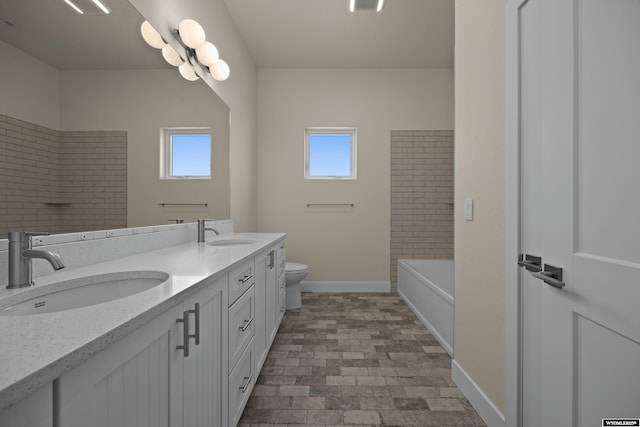 bathroom featuring plenty of natural light, baseboards, toilet, and double vanity