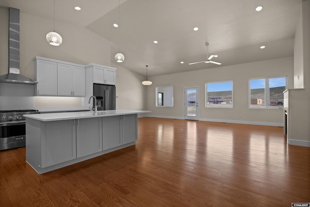 kitchen featuring high quality appliances, wall chimney range hood, ceiling fan, light countertops, and high vaulted ceiling