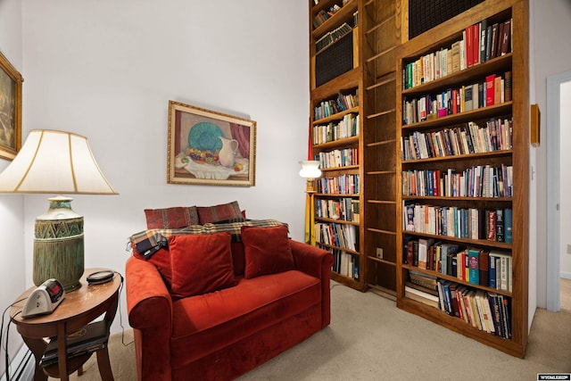 sitting room featuring bookshelves and carpet