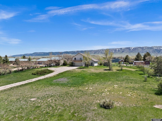 view of front facade with a mountain view, dirt driveway, a garage, and a front lawn