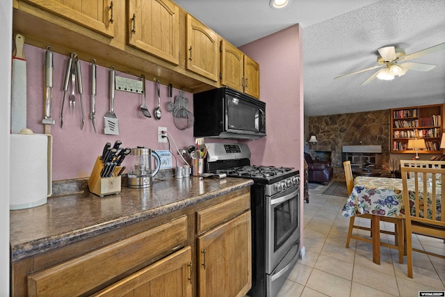 kitchen with stainless steel range with gas stovetop, black microwave, ceiling fan, dark countertops, and light tile patterned floors