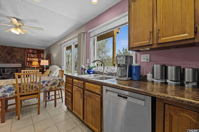 kitchen with dishwasher, a sink, dark countertops, brown cabinetry, and a ceiling fan