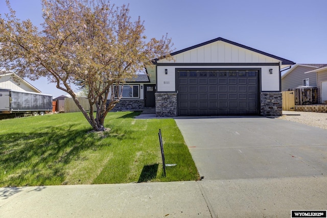 view of front of property with stone siding, a front yard, driveway, and a garage