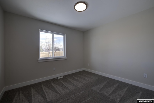 unfurnished room featuring dark carpet and baseboards