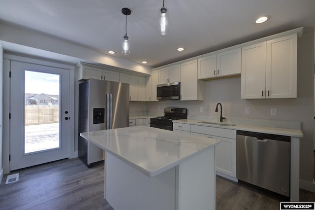 kitchen featuring stainless steel appliances, a sink, dark wood-type flooring, a center island, and recessed lighting