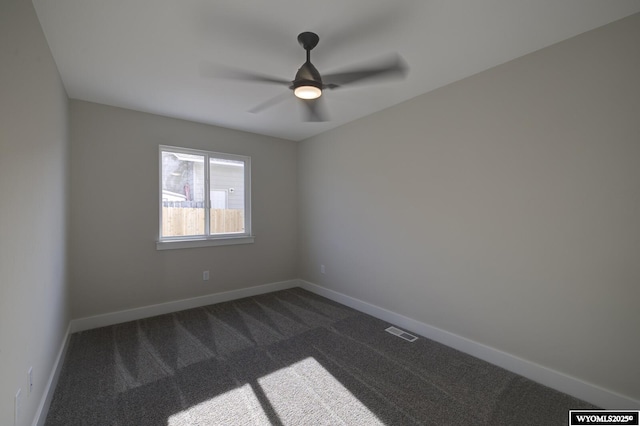 spare room featuring dark colored carpet, baseboards, and ceiling fan