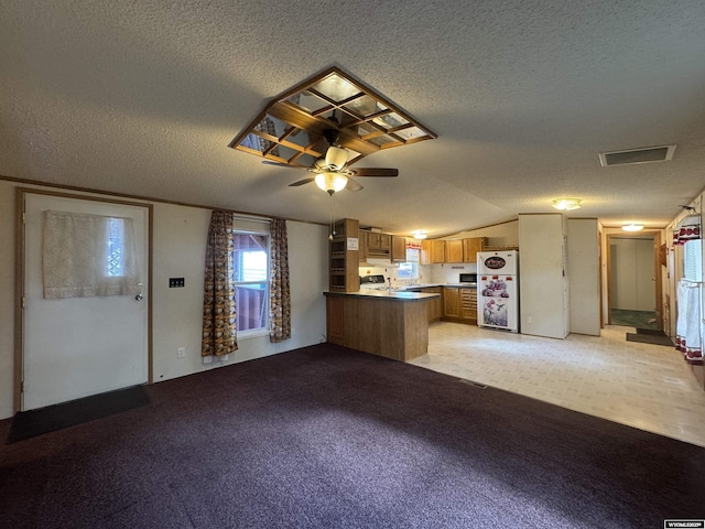 1414 Eileen St, Riverton, WY 82501 - kitchen with freestanding refrigerator, a textured ceiling, brown cabinetry, a peninsula, and a ceiling fan