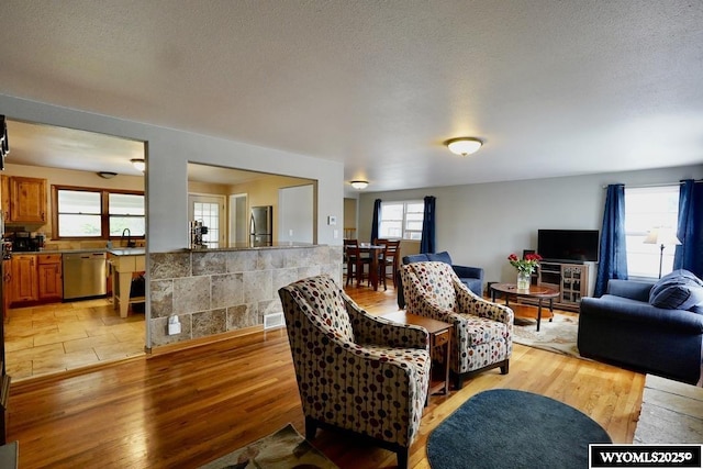 living area with healthy amount of natural light, light wood-type flooring, and a textured ceiling