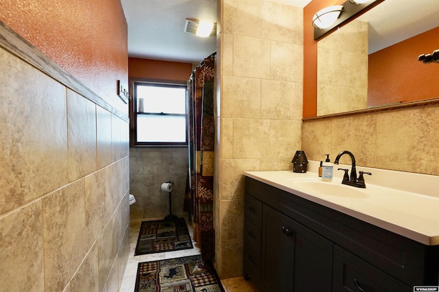 bathroom with tile walls, vanity, and toilet