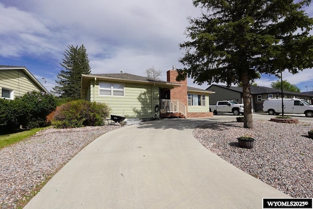 bungalow-style house with a chimney and curved driveway