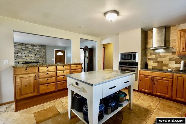 kitchen with wall chimney range hood, appliances with stainless steel finishes, open shelves, brown cabinetry, and backsplash