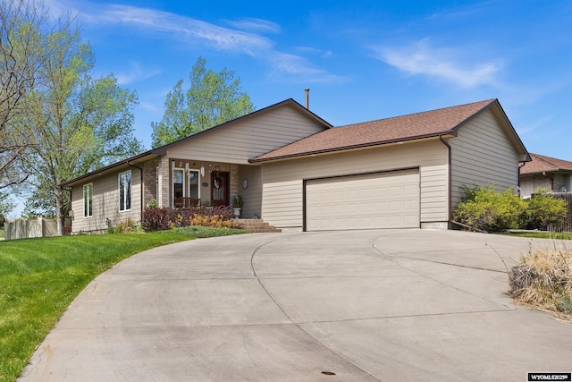 ranch-style home featuring an attached garage, concrete driveway, covered porch, and a front yard