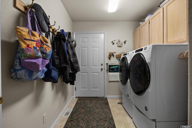 washroom featuring washing machine and dryer, cabinet space, baseboards, and light tile patterned floors
