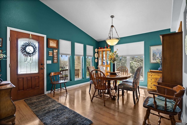 dining area featuring vaulted ceiling, wood finished floors, and baseboards
