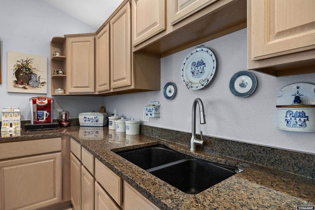 kitchen featuring a sink, light brown cabinetry, open shelves, dark stone countertops, and vaulted ceiling