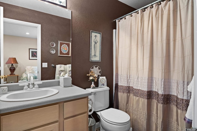 full bath with a textured wall, vanity, toilet, and curtained shower