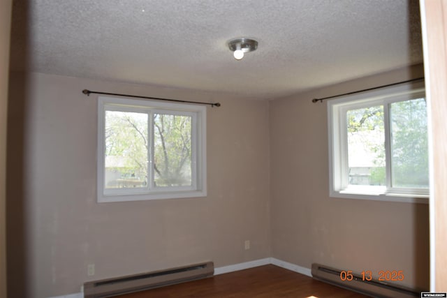 spare room with a baseboard radiator, baseboard heating, healthy amount of natural light, a textured ceiling, and baseboards