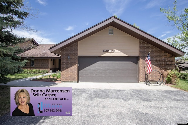 view of front of property with brick siding, an attached garage, and asphalt driveway