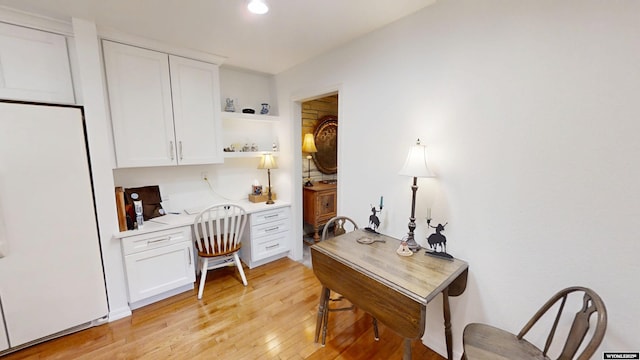 office space featuring light wood finished floors, built in desk, and recessed lighting