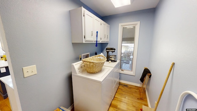 washroom with cabinet space, washer and clothes dryer, light wood-type flooring, and baseboards