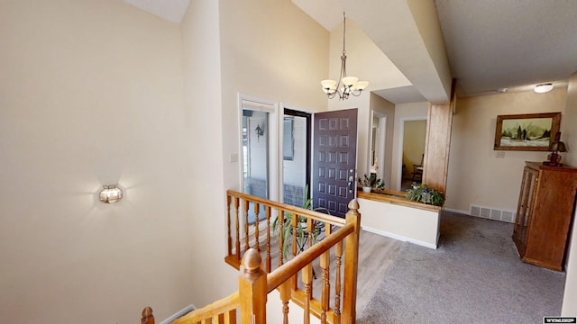 corridor featuring a chandelier, baseboards, an upstairs landing, and carpet floors