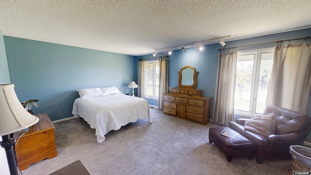 bedroom with track lighting, carpet floors, and a textured ceiling