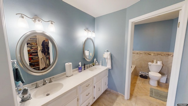 bathroom featuring toilet, double vanity, tile patterned flooring, and a spacious closet