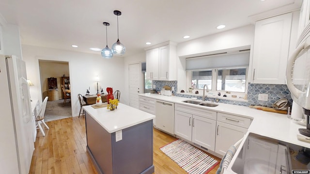 kitchen featuring a sink, white appliances, light wood finished floors, decorative backsplash, and recessed lighting