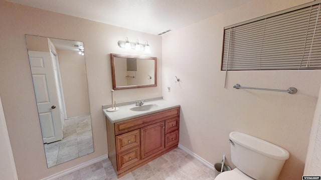 bathroom featuring toilet, vanity, and baseboards