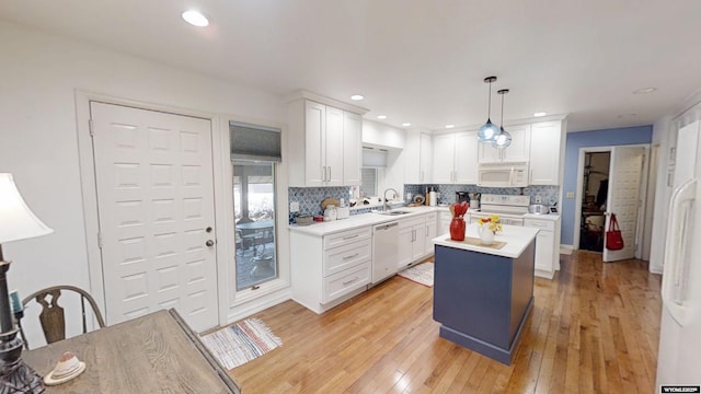 kitchen featuring white appliances, a sink, light countertops, decorative backsplash, and recessed lighting
