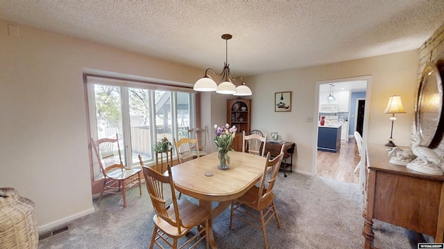 dining room with carpet, a textured ceiling, and baseboards