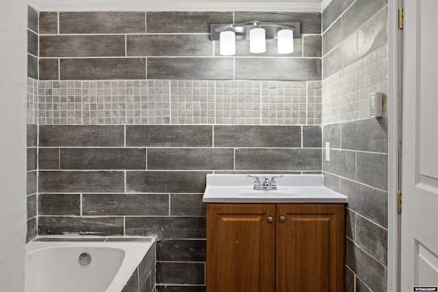 bathroom featuring tiled tub, vanity, and tile walls