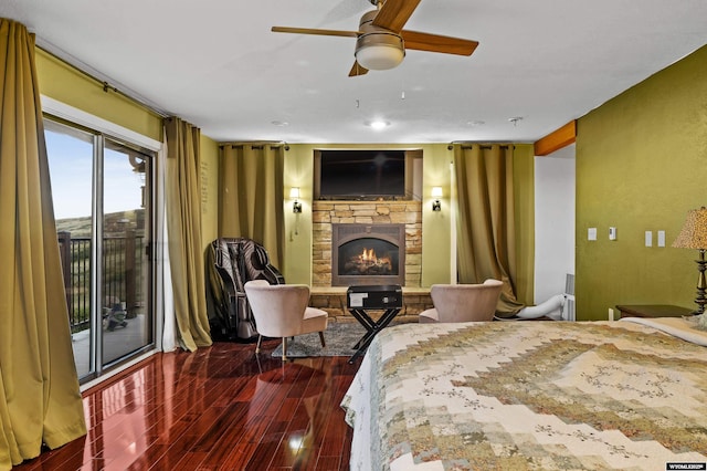 bedroom with access to outside, a stone fireplace, and dark wood-style flooring