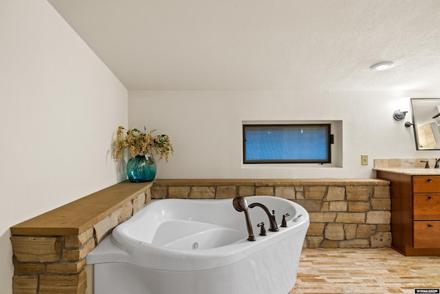 bathroom featuring a jetted tub, vanity, and wood finished floors