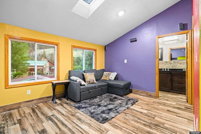 living area featuring vaulted ceiling, a skylight, wood finished floors, and baseboards