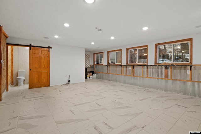 below grade area featuring recessed lighting, marble finish flooring, a barn door, and a fireplace