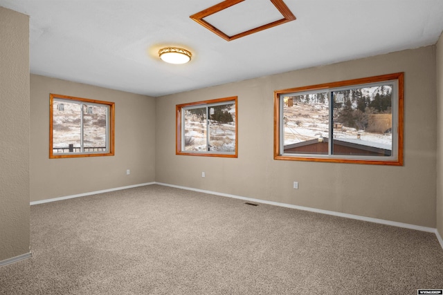 spare room with carpet floors, baseboards, and attic access