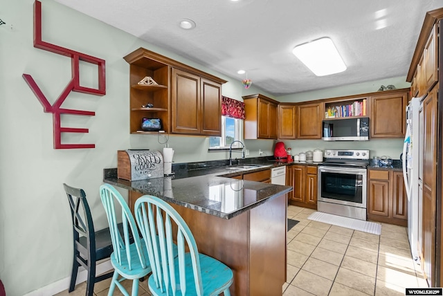 104 Canyon Hollow Dr, Evanston, WY 82930 - kitchen featuring open shelves, appliances with stainless steel finishes, a peninsula, a sink, and brown cabinetry