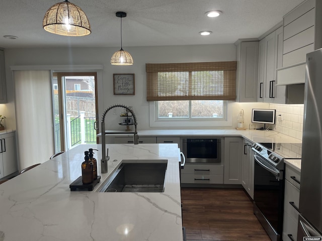 2715 Colorado Dr, Green River, WY 82935 - kitchen with appliances with stainless steel finishes, a sink, hanging light fixtures, light stone counters, and decorative backsplash
