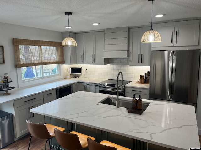 2715 Colorado Dr, Green River, WY 82935 - kitchen with gray cabinets, premium range hood, appliances with stainless steel finishes, backsplash, and light stone countertops