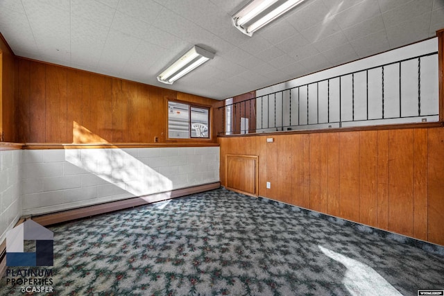 unfurnished room featuring carpet and wood walls