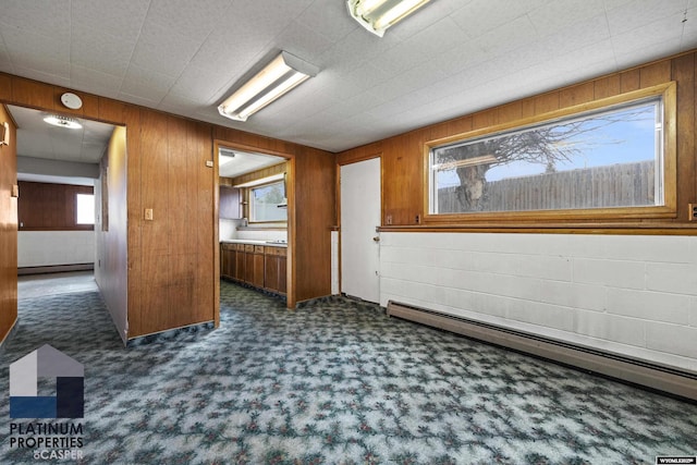 carpeted spare room with baseboard heating, wood walls, and a smoke detector