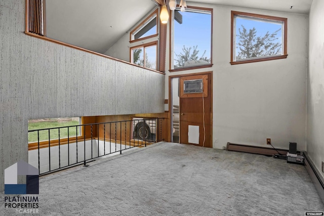spare room with high vaulted ceiling, carpet, plenty of natural light, and a baseboard heating unit