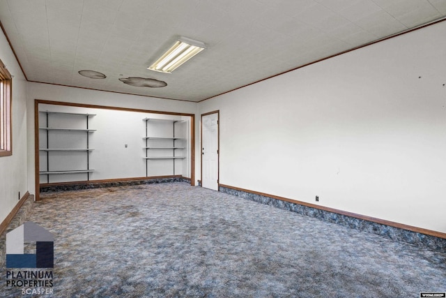 carpeted empty room featuring built in features and baseboards